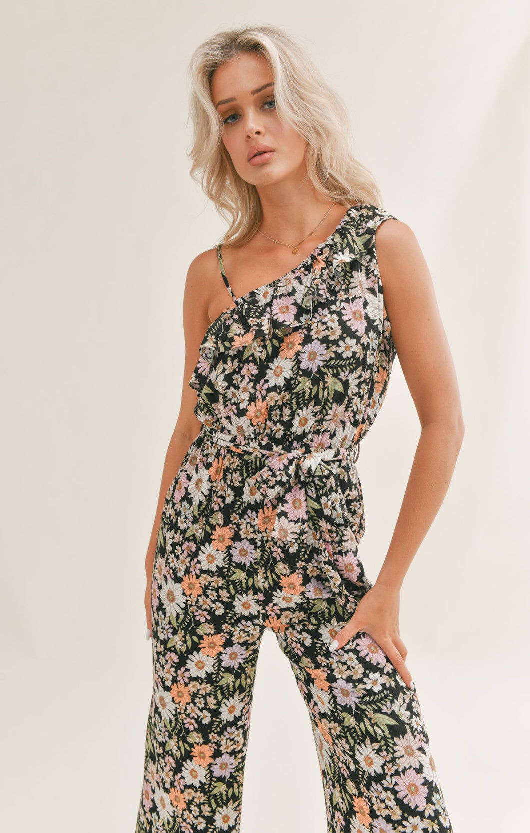 Model wearing Sadie & Sage - Getaway Garden One Shoulder Jumpsuit in Black Multi.